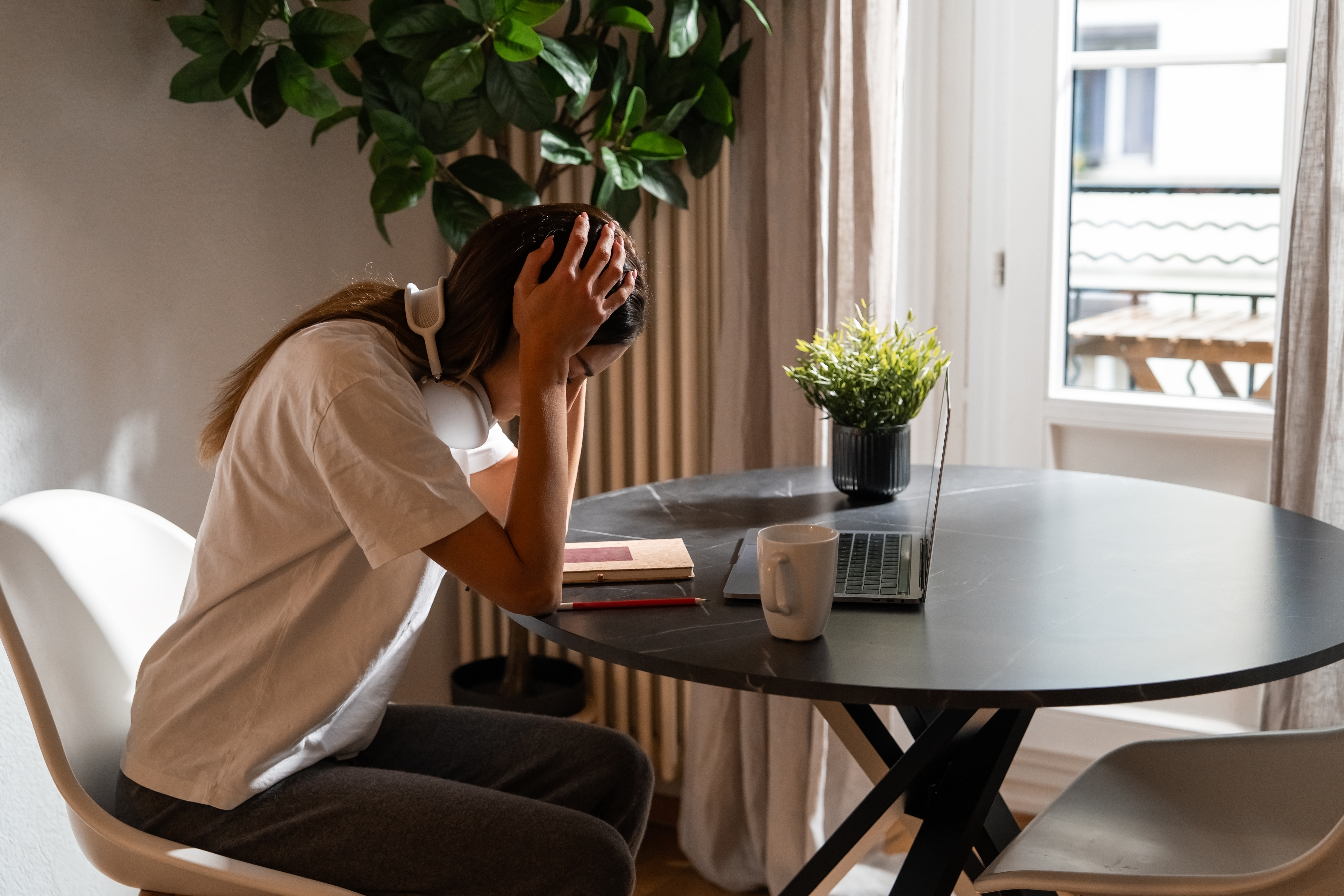 Exhausted,Young,Woman,Sitting,At,Home,With,Laptop,Holding,Her