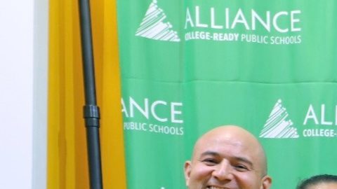 Estudiantes y familias de Alliance College-Ready Public Schools posan junto a Tyrone Nance, director ejecutivo de Its Bigger Than You (IBTU), durante un evento comunitario de colaboración que brindó recursos esenciales y apoyo a los estudiantes y sus familias.