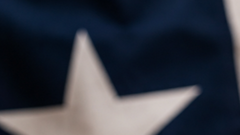 Mazo de juez y balanza de la justicia con la bandera de Texas desenfocada al fondo, en referencia a la orden ejecutiva de Greg Abbott contra el llamado "birth tourism".