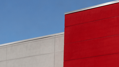 Fachada exterior de una tienda Target con su característico frente rojo, puertas de entrada vidriadas y un carrito rojo en primer plano.