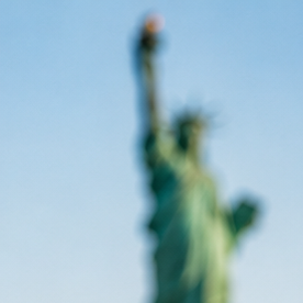 Green Card, pasaporte y bandera de Estados Unidos con la Estatua de la Libertad y el skyline de Nueva York al fondo.