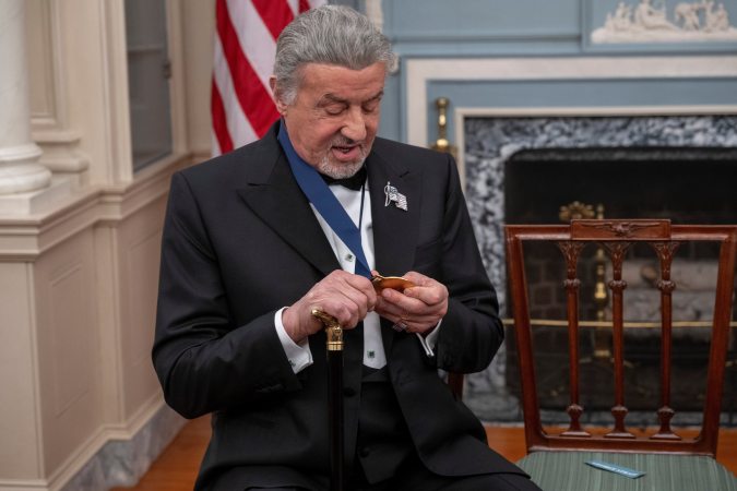 The 2025 Kennedy Center Honoree Sylvester Stallone looks at his medallion during the 48th Kennedy Center Honors Medallion Reception, hosted at the U.S. Department of State, Saturday, Dec. 6, 2025 in Washington.