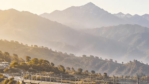 Tren moderno cruza el puente Chenab sobre un valle montañoso del Himalaya en India